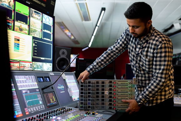 an on-call engineer working at broadcast control desk with monitors and tools