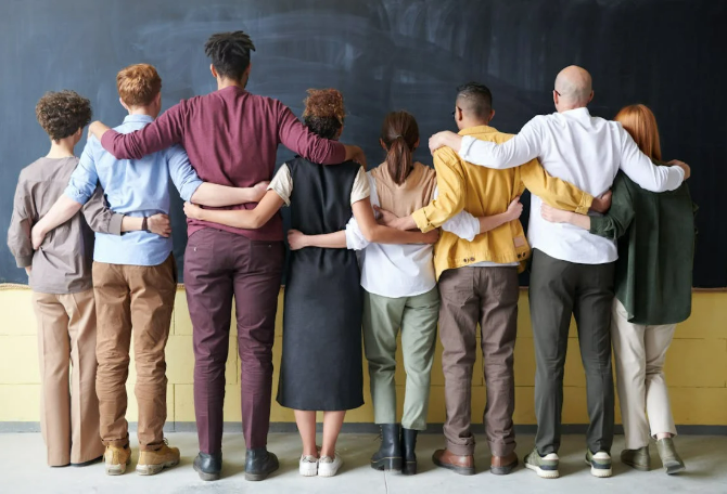  A diverse team stands arm in arm, symbolizing unity and strong culture across organizational structures