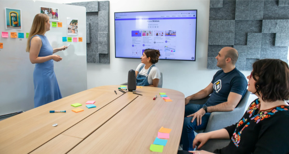 employees at an in-house training session with tools like a digital screen, whiteboard, post its and markers 