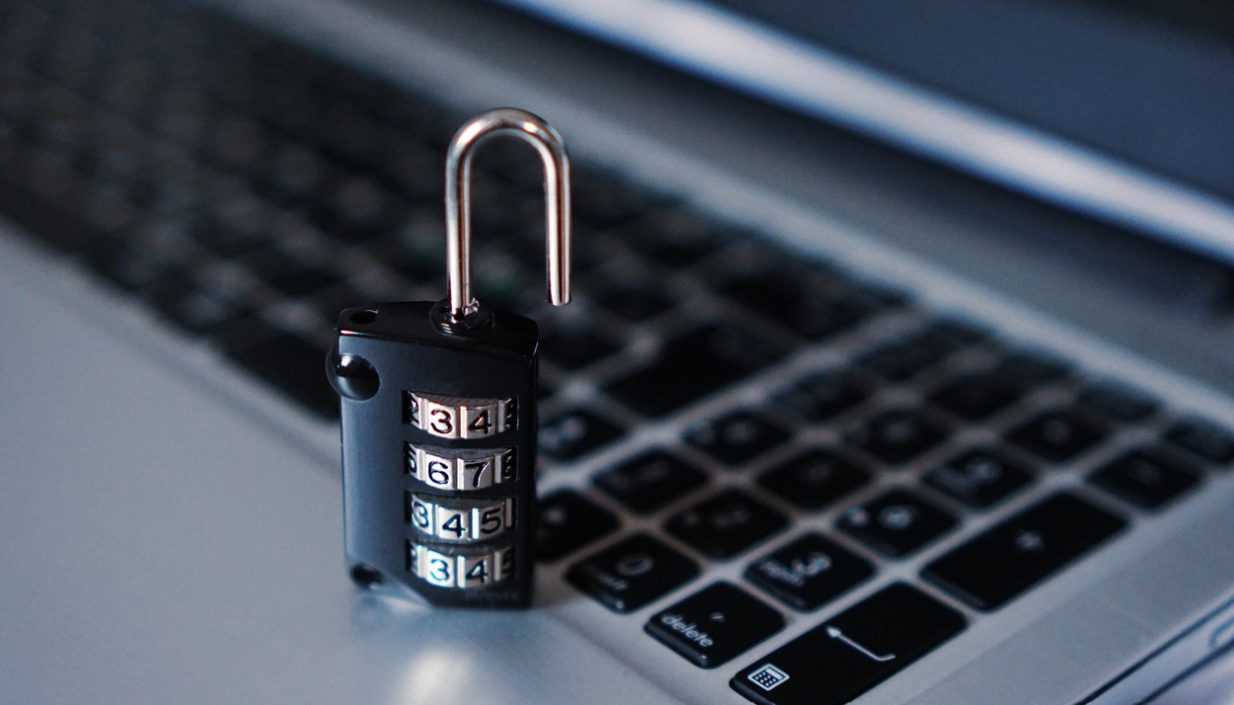 a combination padlock sits on top of a laptop keyboard, symbolic of the need to protect personal data