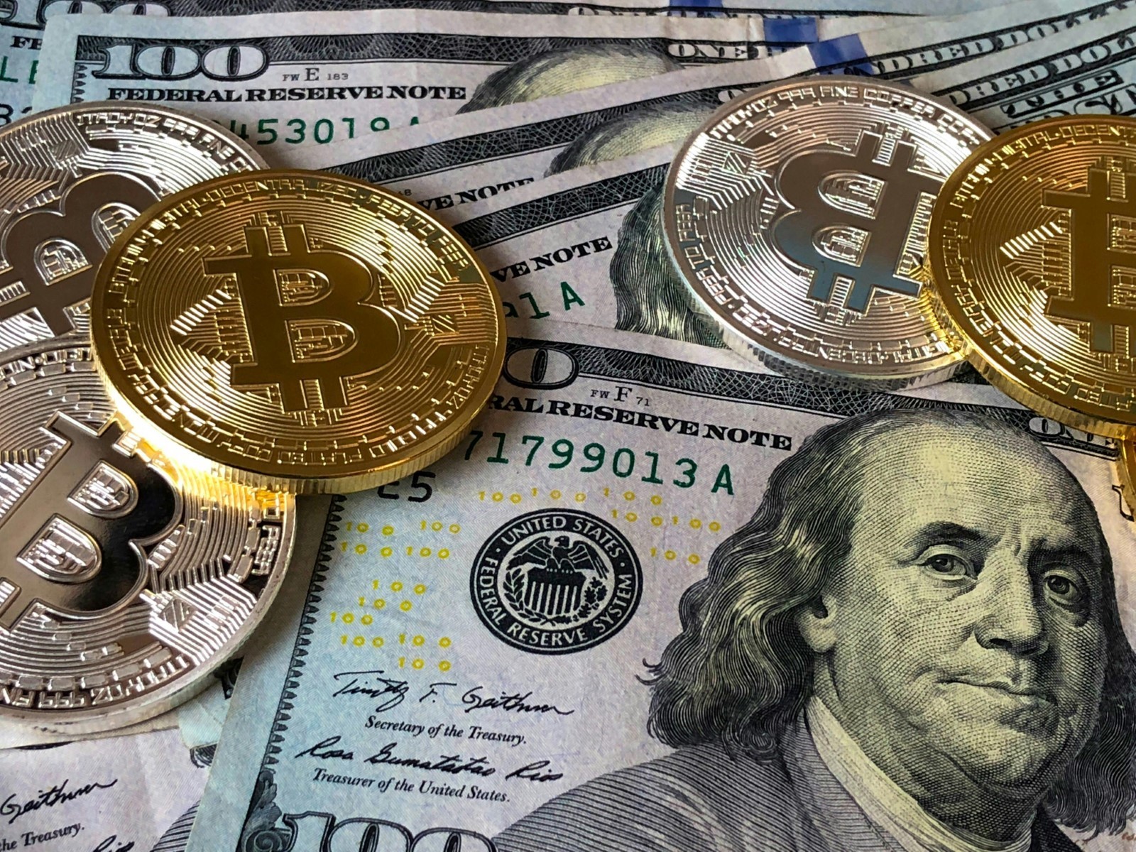 shot of US dollar bills and physical bitcoins