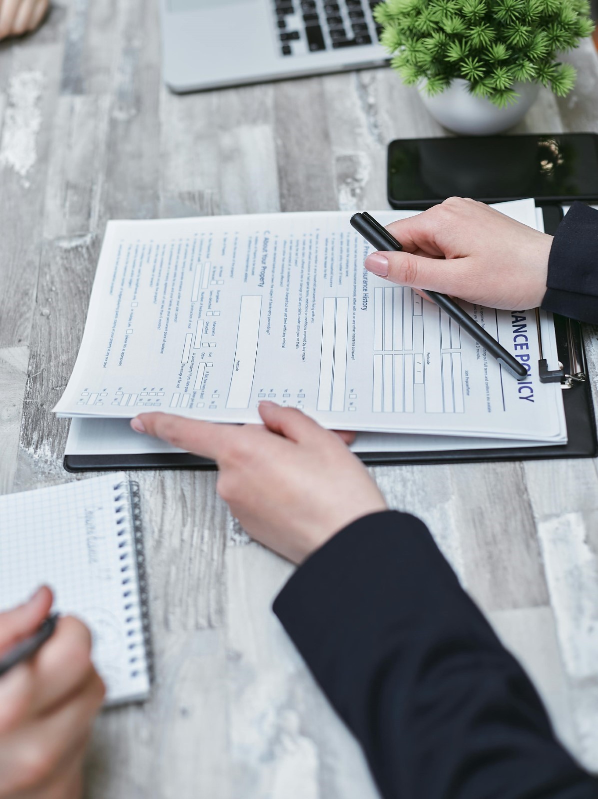 Shot of insurance broker’s hands giving a pen and insurance policy to client for them to sign