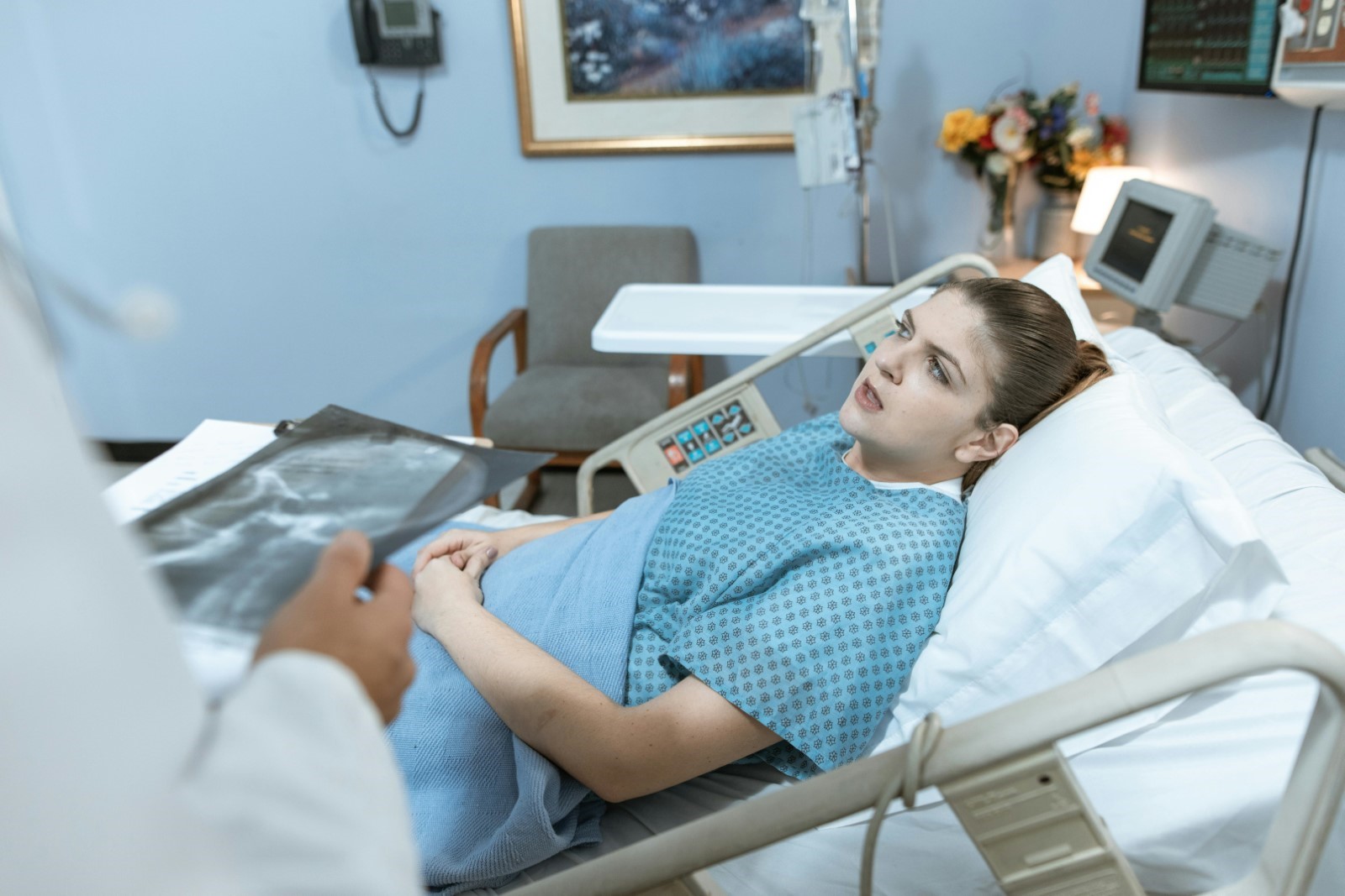 Female patient talking to doctor while lying in hospital bed