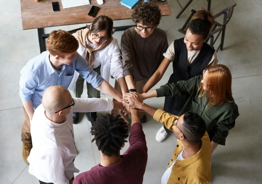 Coworkers joining hands, symbolizing Perkbox's role in fostering team connection and shared support