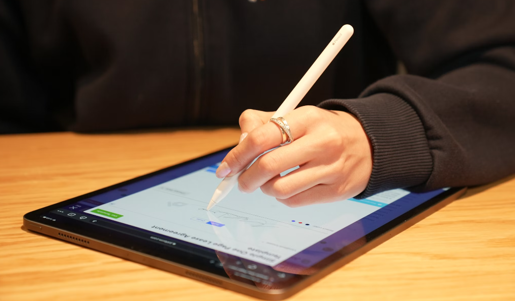 A woman’s hand holding a stylus while signing a document on a mobile tablet