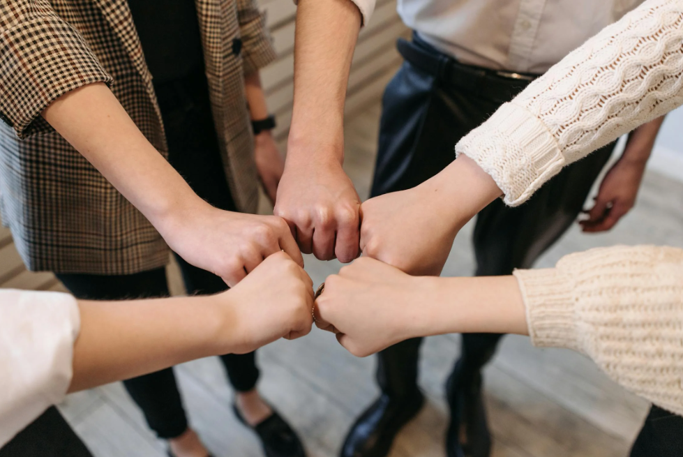 team stacking hands in a circle, showing connection and belonging in the office 
