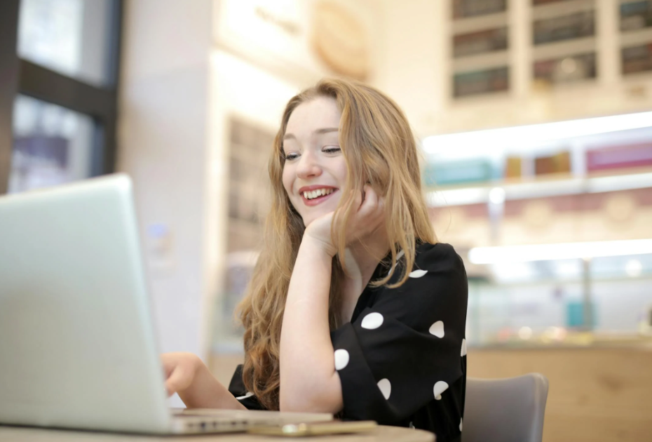 young woman smiling as she looks at the Bonusly announcements page on her laptop