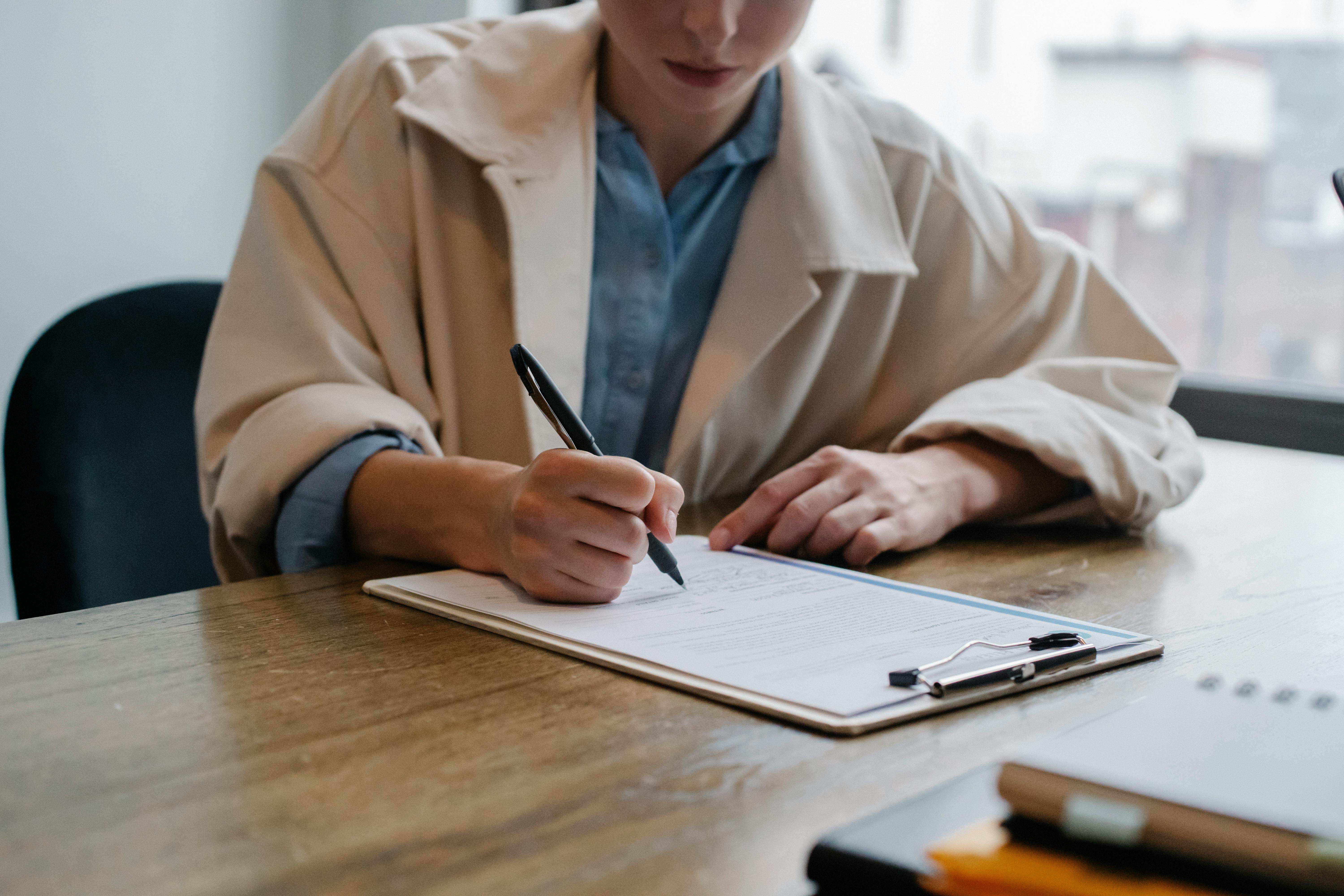 woman signing documents as part of employee onboarding process