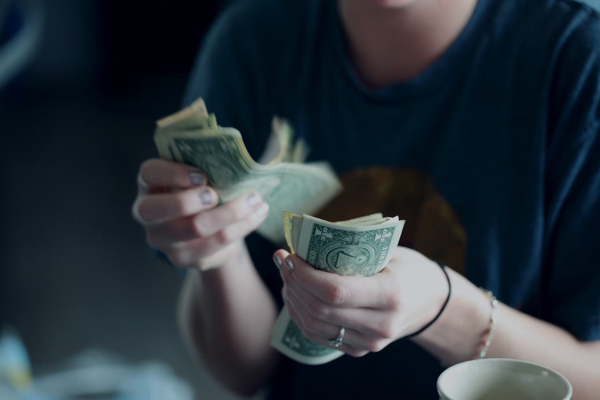 a woman wearing dark blue shirt counting dollar bills to pay her property taxes