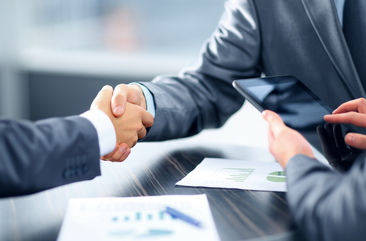 Loan officer shaking hands with a real estate agent – part of the duties of a loan officer is nurturing these relationships