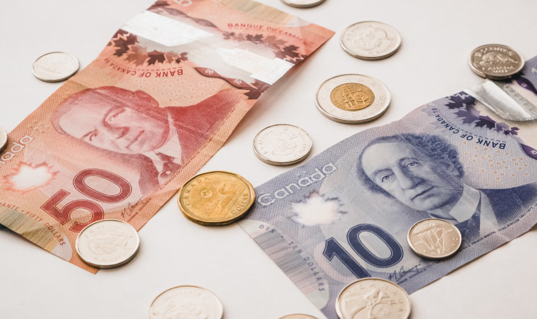 Canadian banknotes and coins symbolizing salary and commissions made by mortgage brokers in Alberta