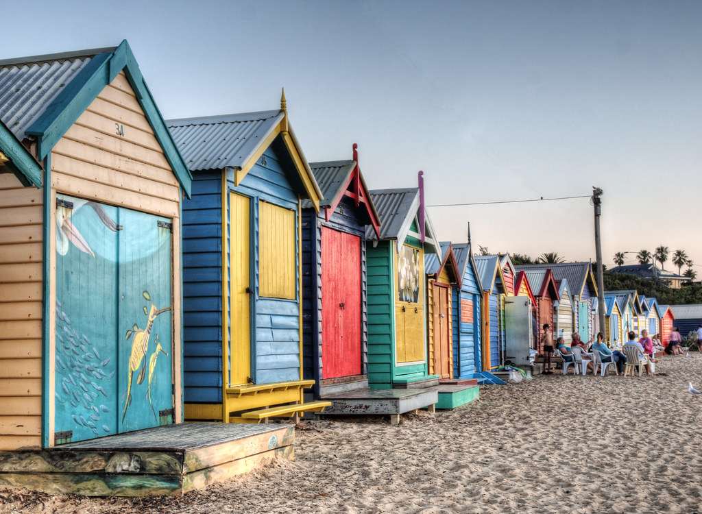 a group of tourists relaxing near the famous Bathing Boxes of Brighton