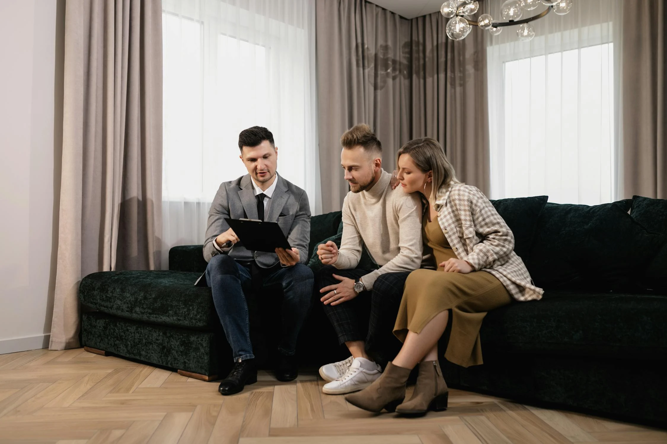 a mortgage broker in gray suit talking to first-time homebuyers