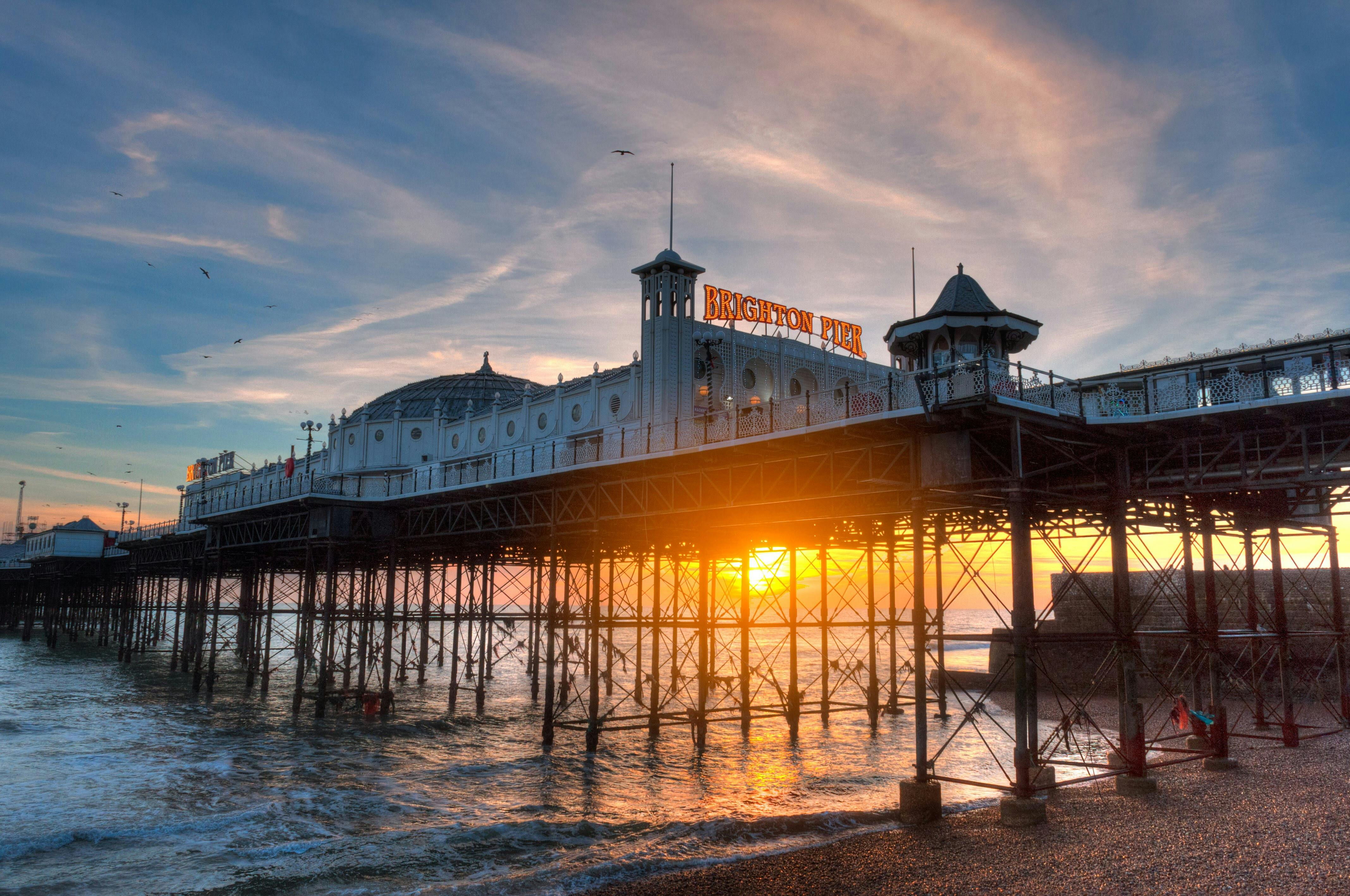 Brighton Pier at low tide with a sunset as backdrop