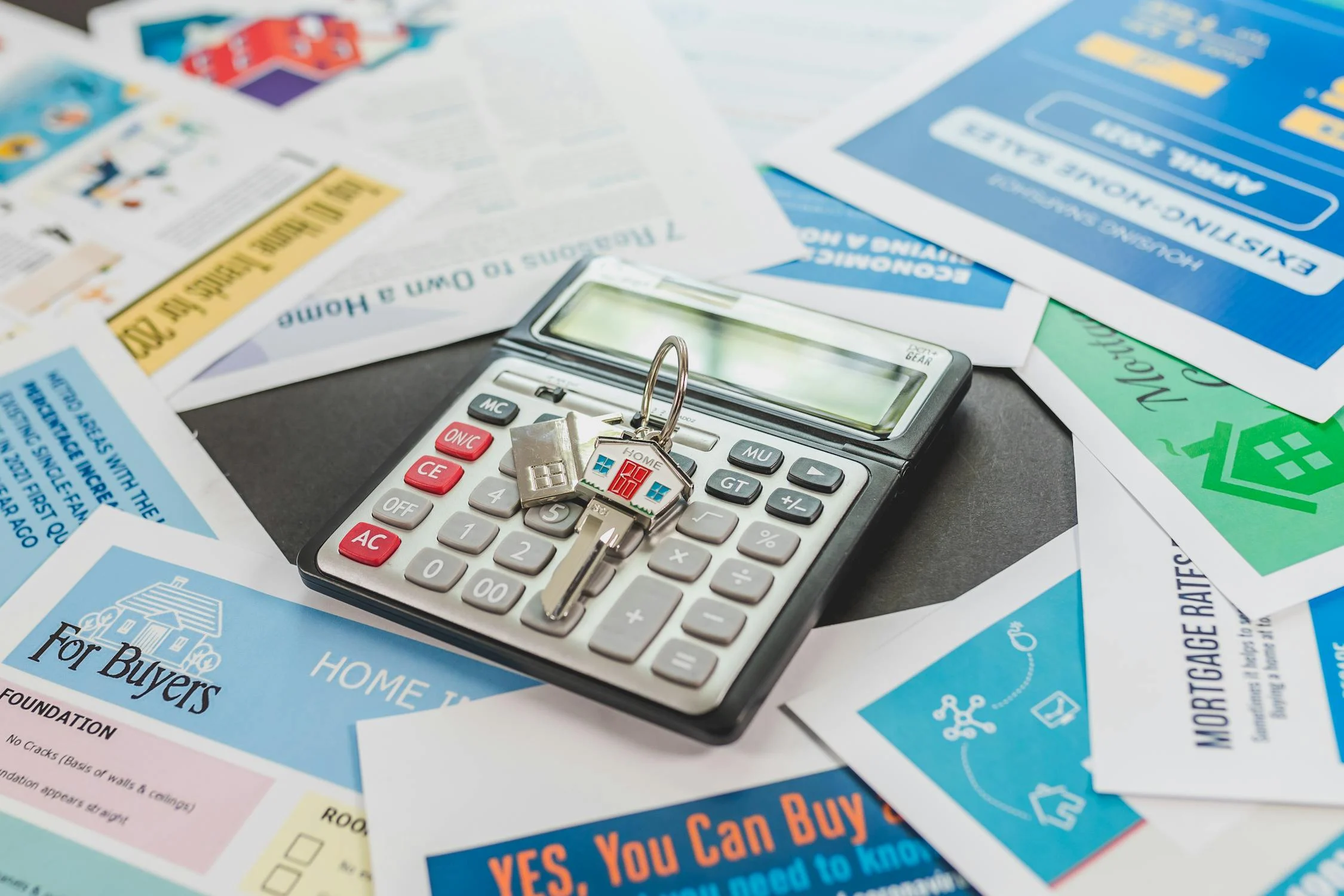 a key with a small house keychain over a calculator to symbolize The Mortgage Works’ mortgage calculator